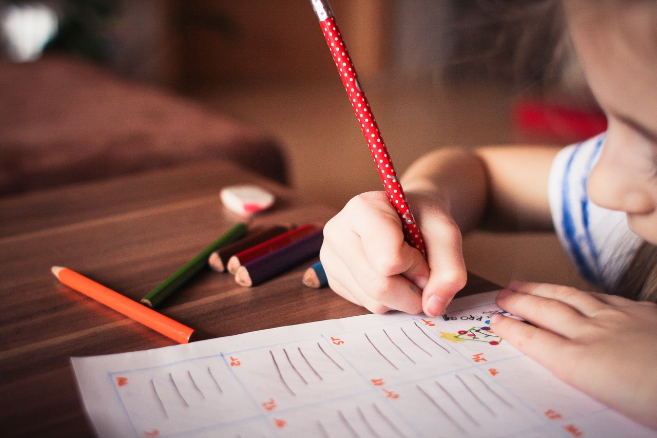Kind aan schooltafel werkt in schoolschrift.